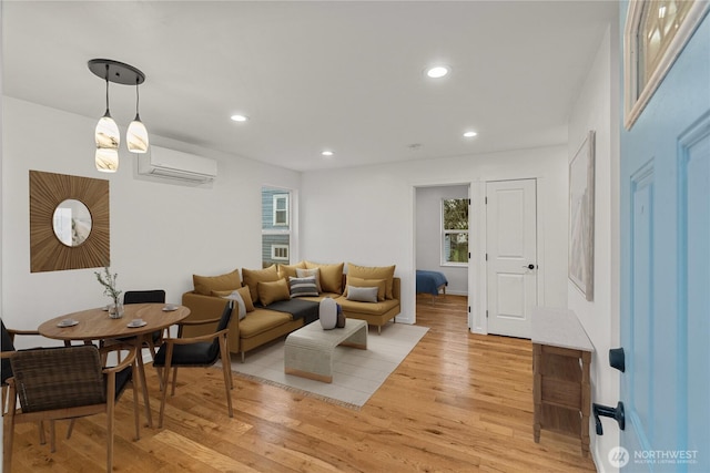 living room featuring a wall mounted air conditioner and light hardwood / wood-style flooring