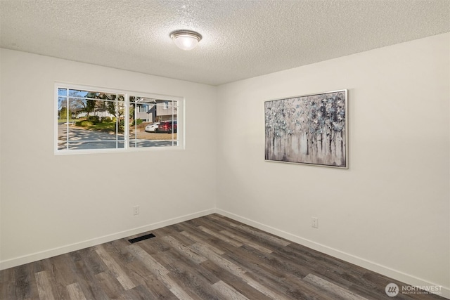 empty room with dark wood-type flooring and a textured ceiling