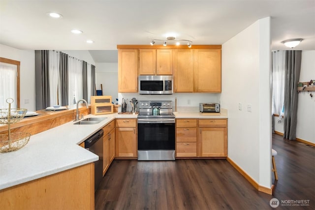 kitchen featuring recessed lighting, light countertops, appliances with stainless steel finishes, dark wood-type flooring, and a sink