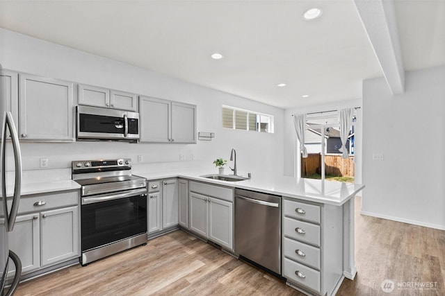 5401 Parkside Dr SE, Lacey, WA 98503 - kitchen featuring appliances with stainless steel finishes, gray cabinets, a peninsula, light wood-style floors, and recessed lighting