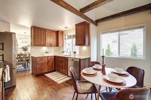 kitchen featuring sink, hanging light fixtures, appliances with stainless steel finishes, dark hardwood / wood-style flooring, and beamed ceiling