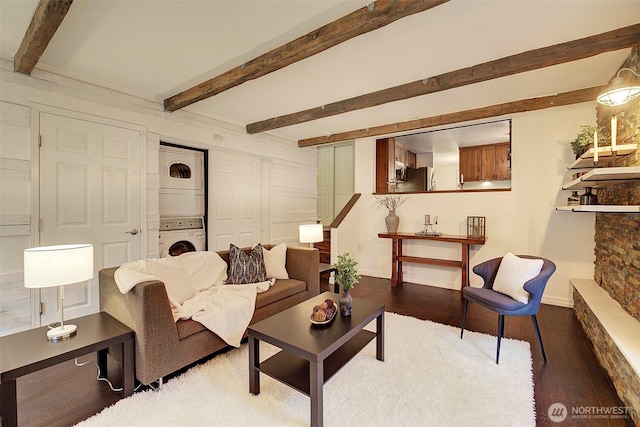 living room featuring stacked washer / drying machine, hardwood / wood-style flooring, and beamed ceiling