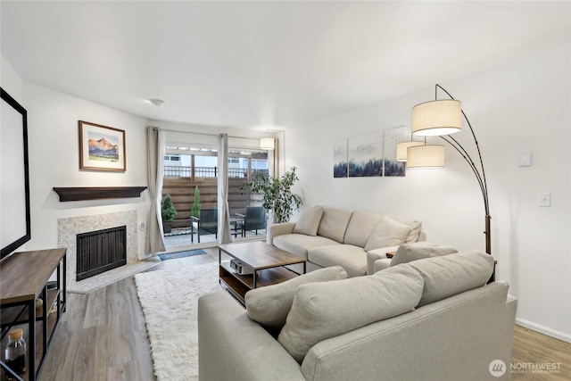 living area with a fireplace with flush hearth, baseboards, and wood finished floors