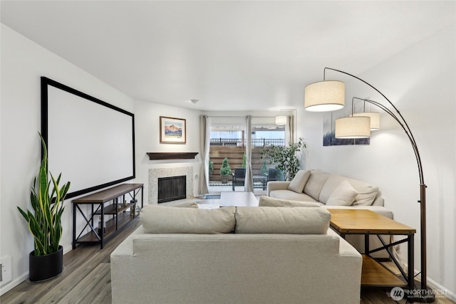 living room with visible vents, baseboards, wood finished floors, and a glass covered fireplace