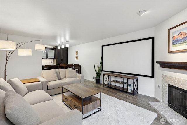 cinema room featuring a fireplace with flush hearth, wood finished floors, and baseboards