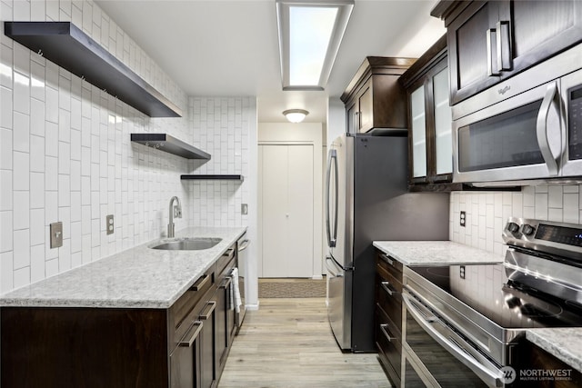 kitchen featuring open shelves, tasteful backsplash, stainless steel appliances, and a sink