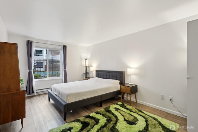 bedroom with baseboard heating, baseboards, and wood finished floors