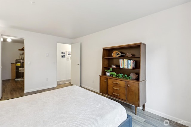 bedroom featuring light wood-type flooring, baseboards, and electric water heater