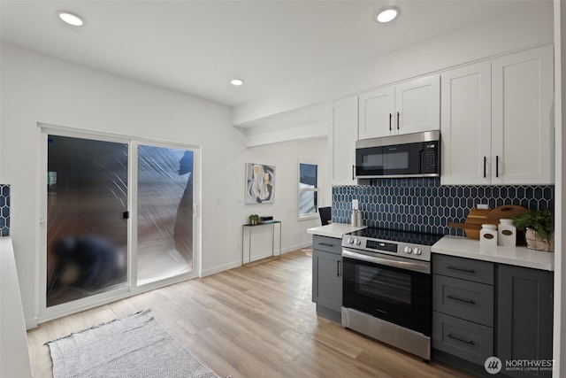 kitchen with stainless steel appliances, white cabinetry, gray cabinets, and light hardwood / wood-style floors