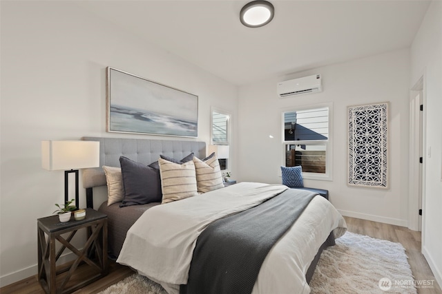 bedroom featuring light wood-type flooring and a wall unit AC