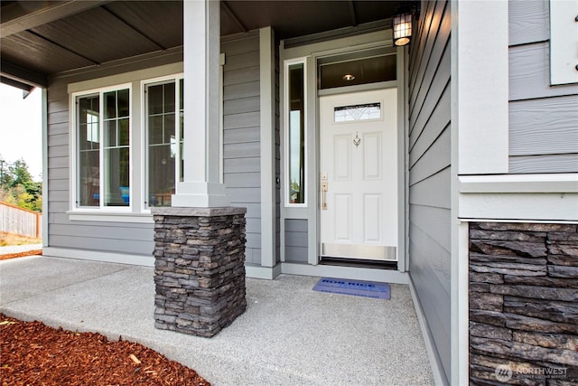 entrance to property with a porch and stone siding