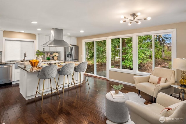 kitchen featuring backsplash, appliances with stainless steel finishes, white cabinets, light stone countertops, and exhaust hood