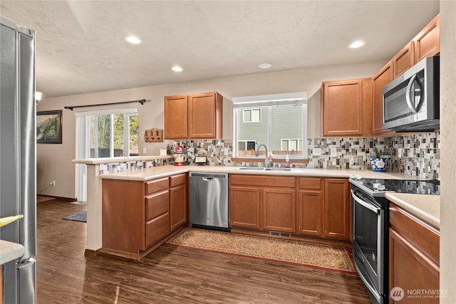 kitchen with sink, stainless steel appliances, dark hardwood / wood-style flooring, decorative backsplash, and kitchen peninsula