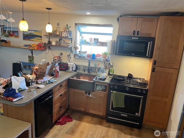 kitchen with light hardwood / wood-style flooring, sink, hanging light fixtures, and black appliances