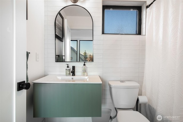 bathroom with vanity, tile walls, and toilet