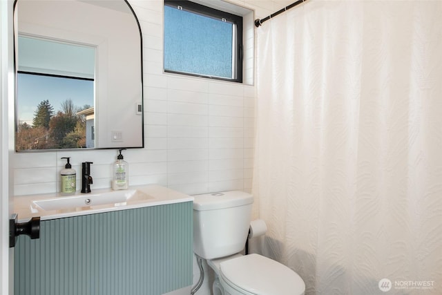 bathroom with vanity, toilet, and tile walls