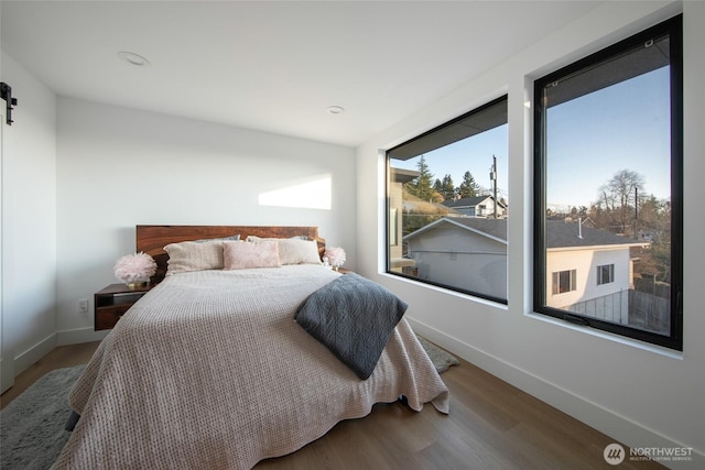 bedroom with hardwood / wood-style flooring and a barn door