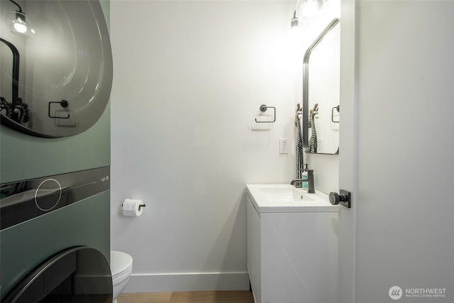 bathroom featuring stacked washer and dryer, vanity, and toilet