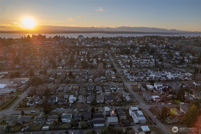 aerial view at dusk featuring a water and mountain view