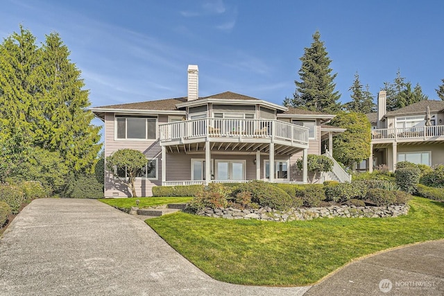 back of property featuring a yard, a chimney, and a wooden deck