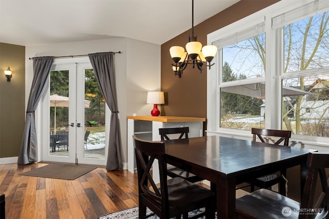 dining area with an inviting chandelier, wood-type flooring, french doors, and a healthy amount of sunlight