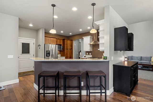 kitchen featuring light stone countertops, appliances with stainless steel finishes, dark hardwood / wood-style flooring, and kitchen peninsula