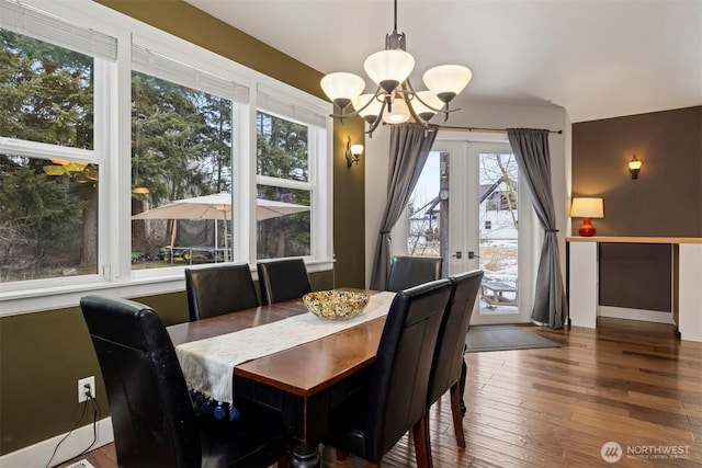 dining area featuring french doors, wood-type flooring, and a notable chandelier