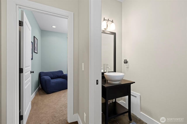 hallway with dark colored carpet and sink