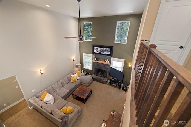 carpeted living room with a high ceiling, plenty of natural light, and ceiling fan