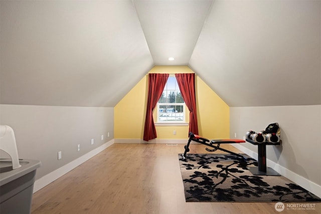 exercise room with lofted ceiling and hardwood / wood-style floors