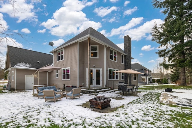 snow covered house with an outdoor living space with a fire pit and french doors