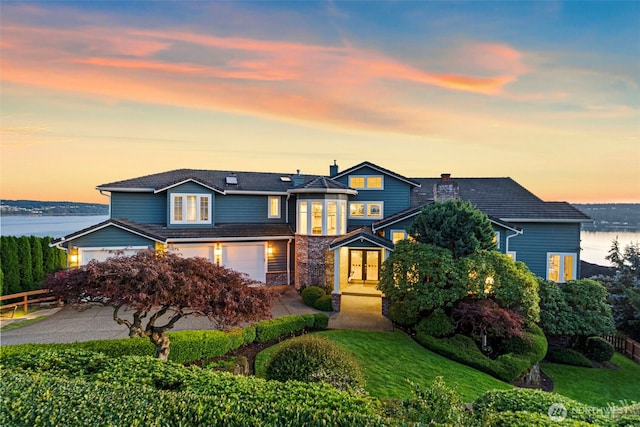 view of front of property with a garage, a lawn, and a water view