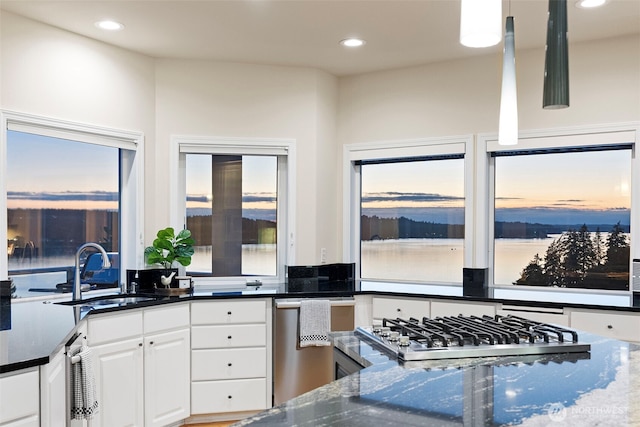 kitchen with stainless steel gas stovetop, sink, white cabinets, and dark stone counters