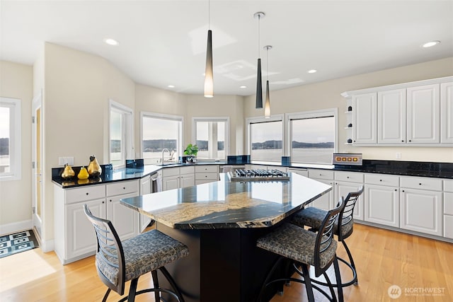 kitchen featuring white cabinetry, a breakfast bar, sink, and hanging light fixtures