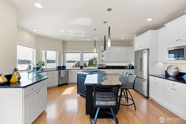 kitchen featuring stainless steel appliances, a kitchen island, sink, and white cabinets