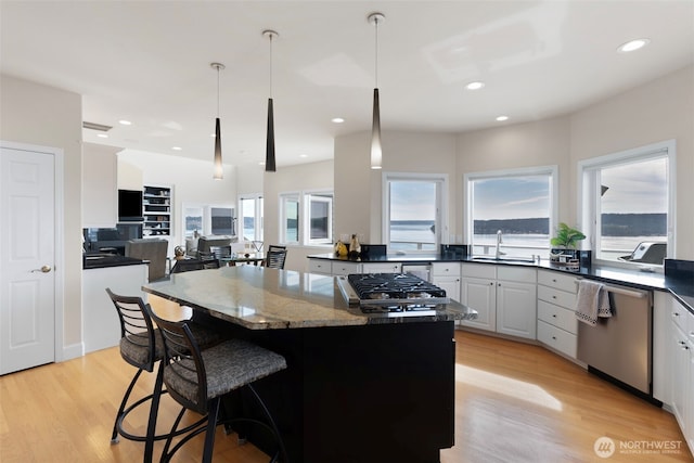 kitchen with sink, white cabinetry, dark stone counters, pendant lighting, and stainless steel appliances