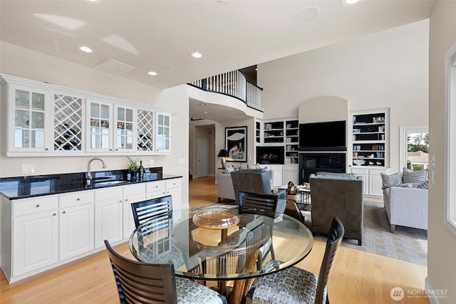 dining space with light hardwood / wood-style flooring, indoor wet bar, and a high ceiling