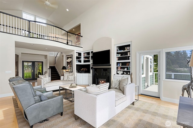 living room featuring high vaulted ceiling, light wood-type flooring, and built in shelves