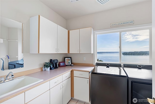 kitchen with white cabinetry, sink, and a water view