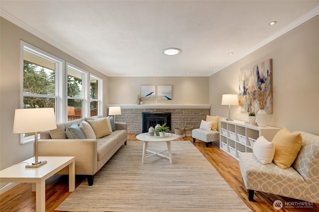 living room featuring ornamental molding, a brick fireplace, and light wood-type flooring