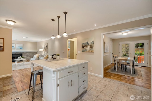 kitchen featuring a breakfast bar area, white cabinetry, hanging light fixtures, a center island, and tile countertops