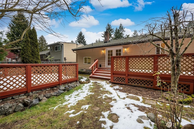 snow covered back of property featuring a wooden deck and french doors