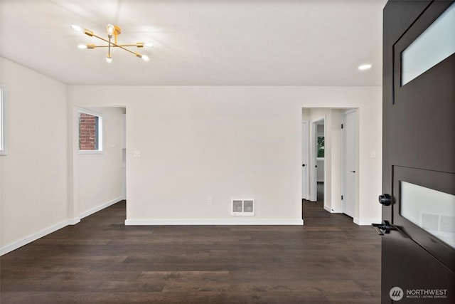 unfurnished room featuring dark hardwood / wood-style flooring and a chandelier