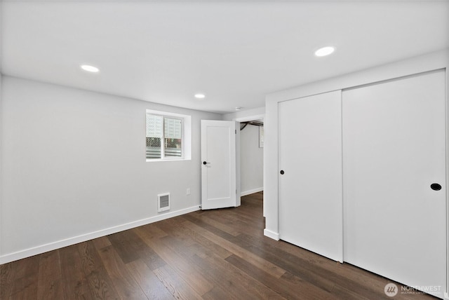 unfurnished bedroom with dark wood-type flooring and a closet