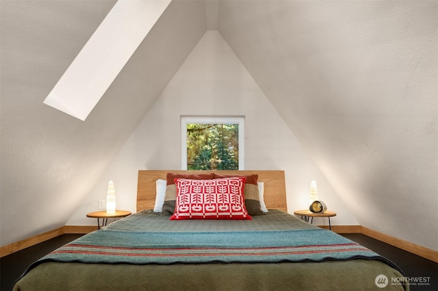 bedroom featuring lofted ceiling with skylight and baseboards