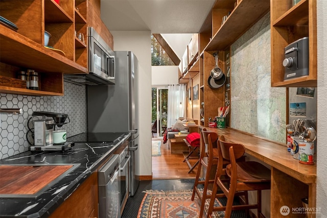 kitchen with brown cabinets, dark wood-type flooring, open shelves, tasteful backsplash, and stainless steel appliances