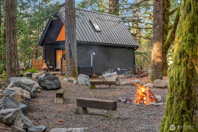 view of side of home featuring metal roof, a fire pit, and a standing seam roof