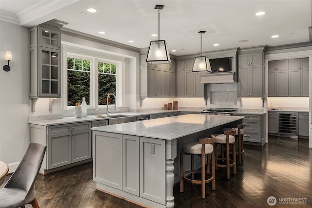 kitchen featuring crown molding, hanging light fixtures, a center island, wine cooler, and light stone countertops