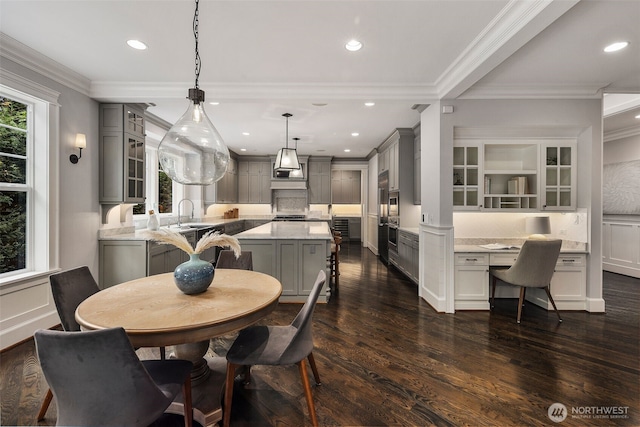 dining space with crown molding, dark hardwood / wood-style floors, built in desk, and sink