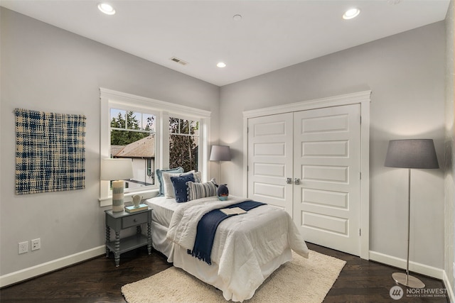 bedroom with dark hardwood / wood-style floors and a closet